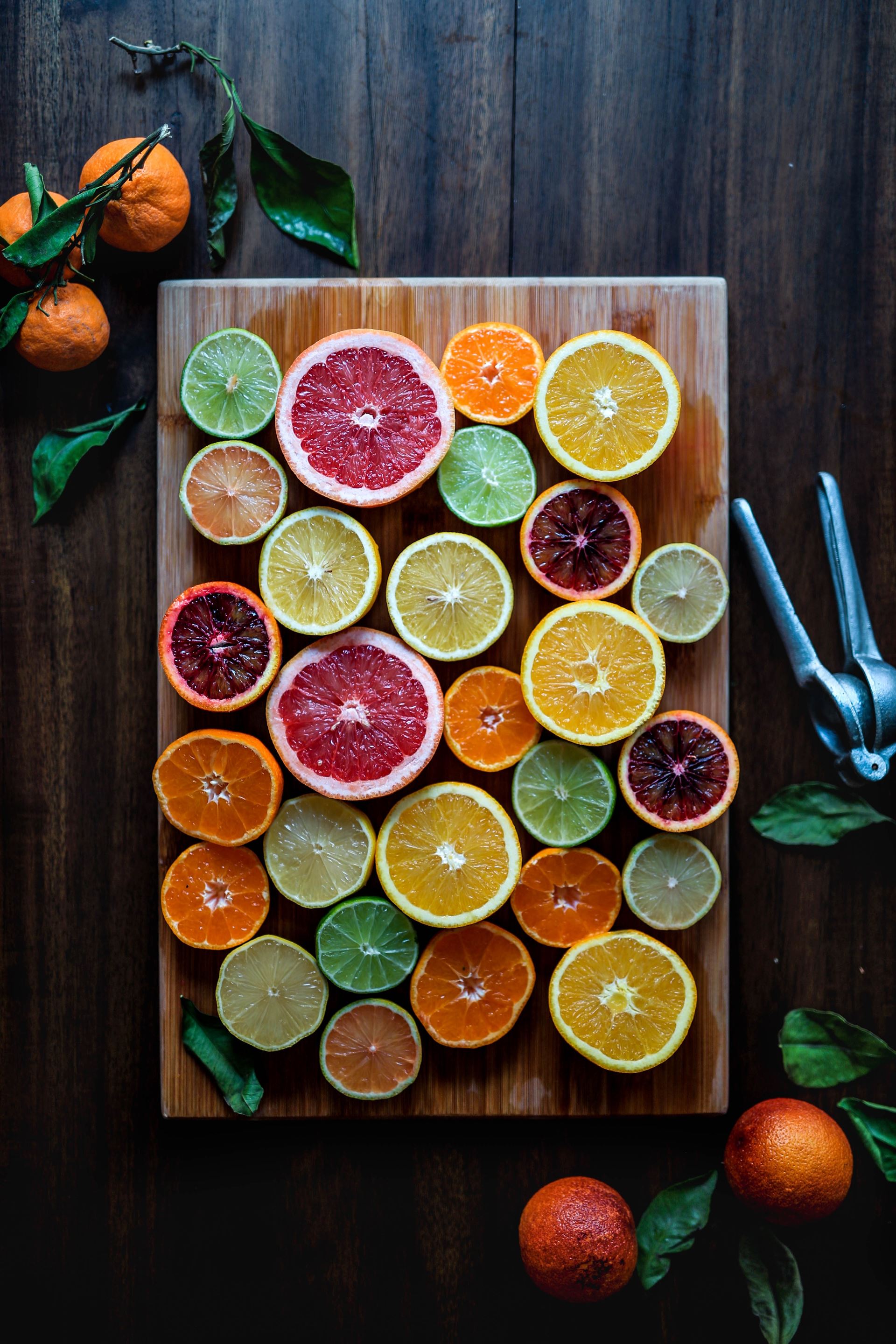 wooden chopping board covered in halved citrus fruits