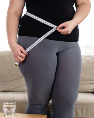 overweight lady measures her waist with a tape measure
