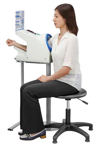 Lady sits at the blood pressure machine with her arm inside